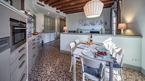 Una cocina moderna con horno empotrado y comedor con mesa dispuesta para cuatro.