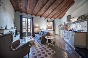 A cozy living room with a sofa, a dining table, and a kitchen area with cabinets and a countertop. - Alaia 21 - Habitat Apartments (Barcelona)