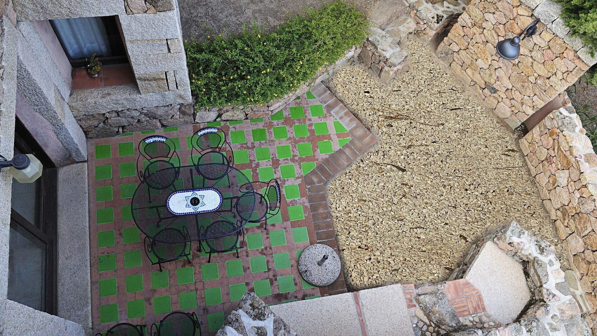 A rooftop patio with a mosaic table, outdoor seating, and a stone wall.
