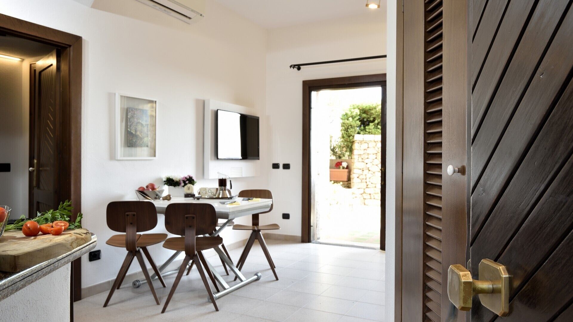 A modern dining area with a table, chairs, and a view of the outdoors.