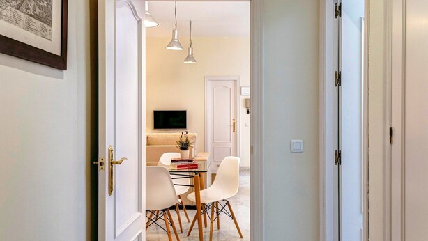 A hallway with a dining area, a TV, and a door leading to another room. - Genteel Home Tomas de Ibarra (Sevilla)