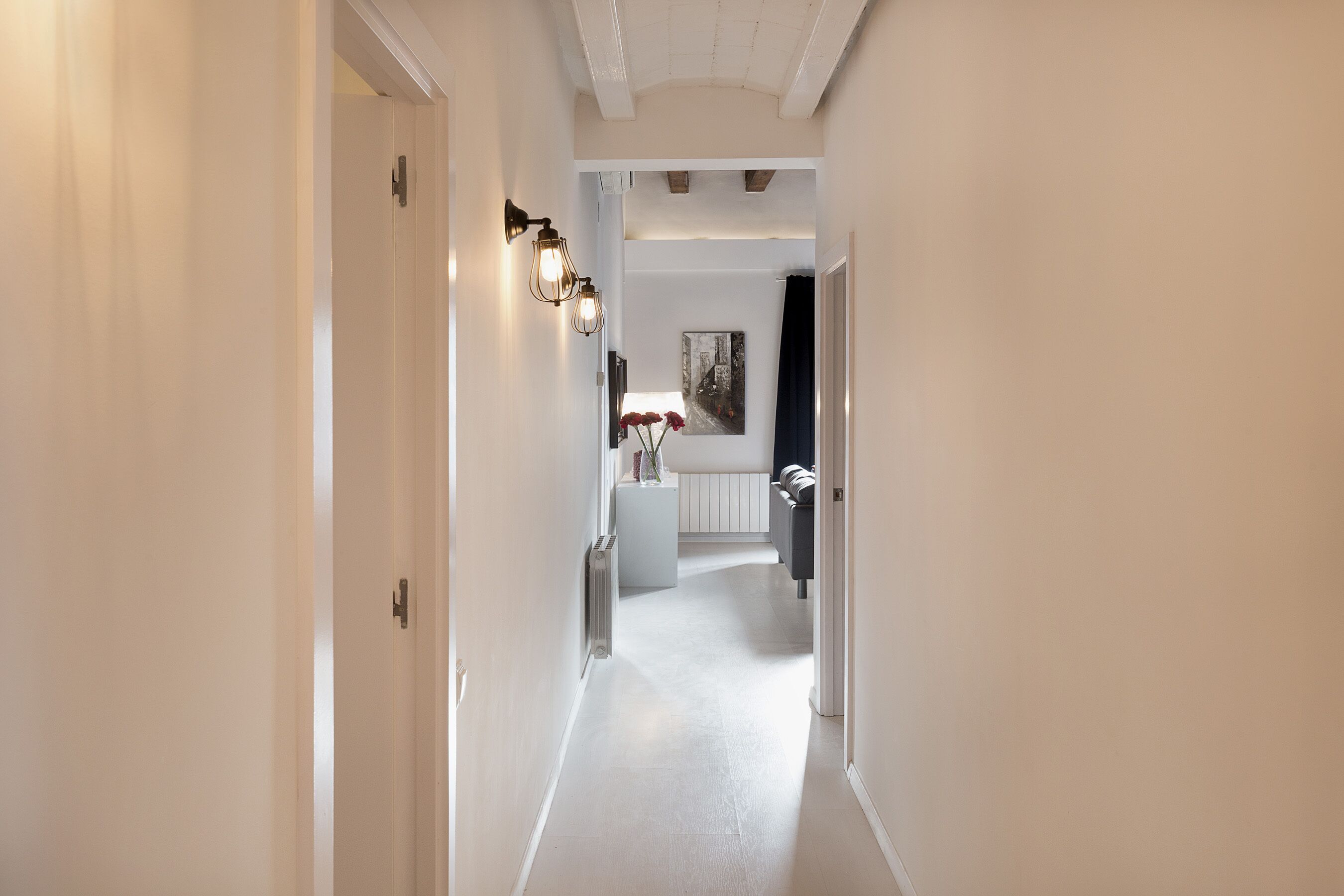 A hallway with white walls, a radiator, and a white door on the left.