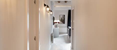 A hallway with white walls, a radiator, and a white door on the left.