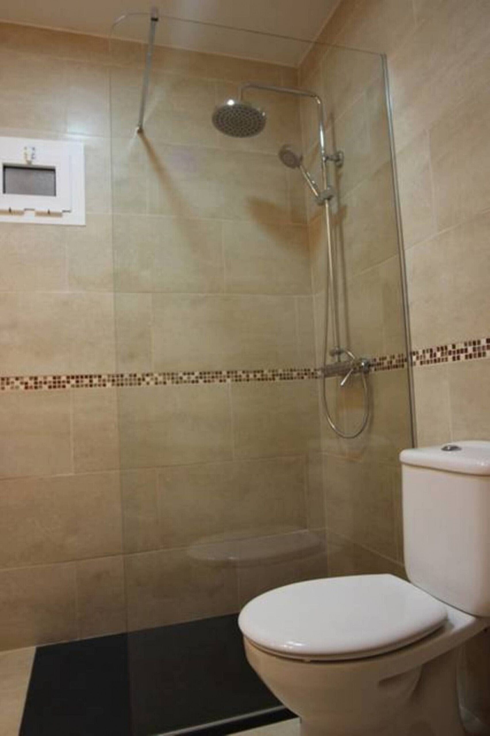 Une salle de bain avec une douche, des toilettes et un petit lavabo.