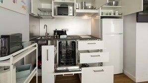 Una cucina compatta con mobili bianchi, un forno a microonde, un piano cottura e una lavastoviglie.