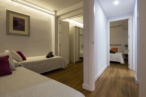 A hotel room with two single beds, a large mirror, and a wooden floor.