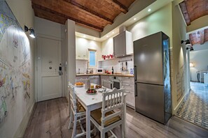 A kitchen with a dining table, chairs, a refrigerator, and a microwave.