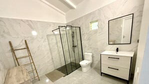 A modern bathroom with a glass shower enclosure, a toilet, and a vanity with drawers.