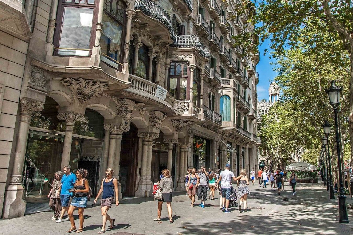 Um edifício histórico com arquitetura elaborada, incluindo colunas e varandas, e uma passarela para pedestres.