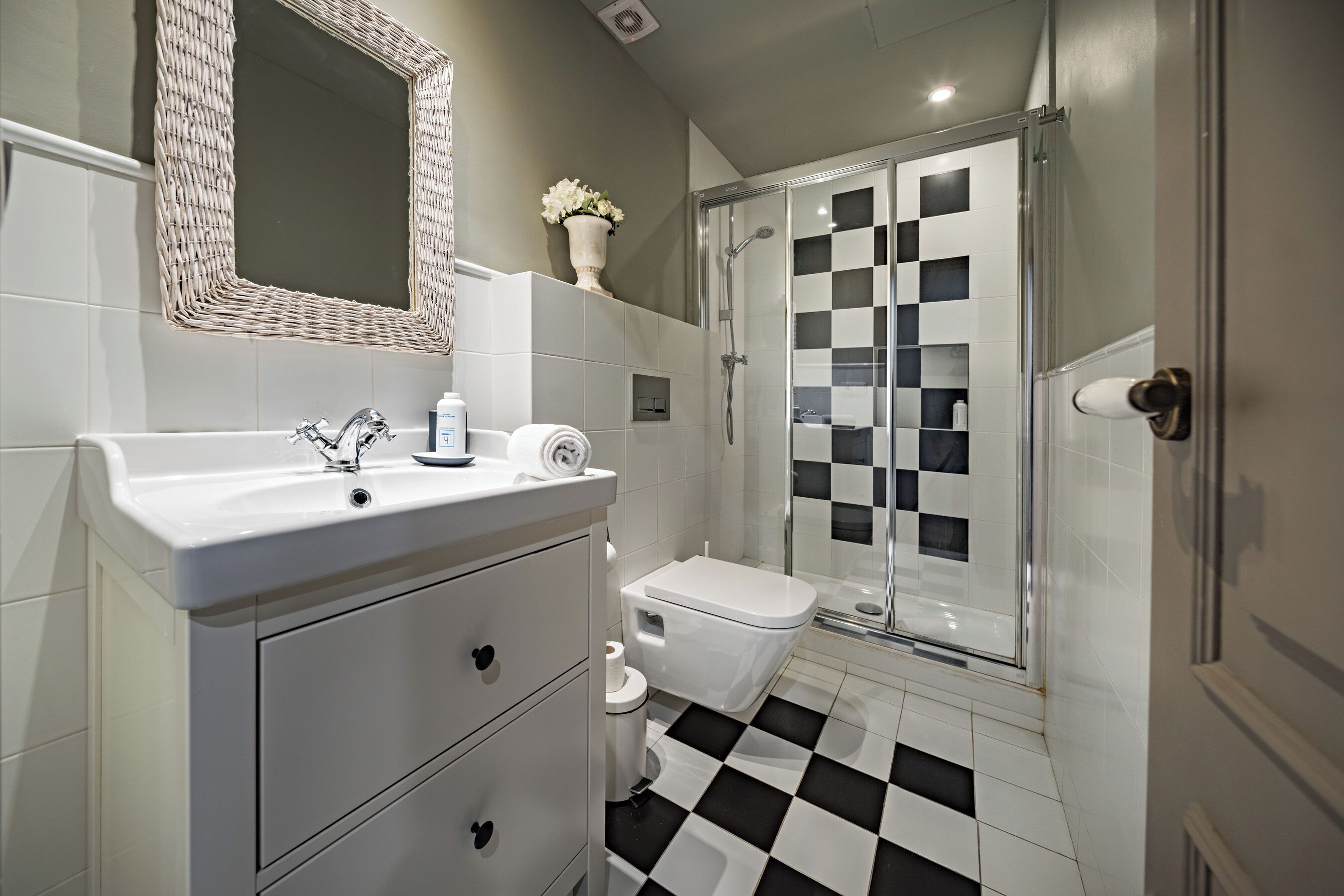 A bathroom with a white sink, a mirror, a toilet, and a shower area.