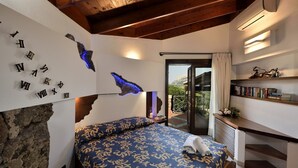 Une chambre avec un lit, un mur en pierre, un balcon avec vue et une bibliothèque.