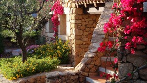 Un bâtiment en pierre doté d’un escalier extérieur en pierre rustique et orné de magnifiques fleurs de bougainvillier aux couleurs vives.