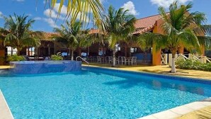 A swimming pool with a small hot tub area, surrounded by palm trees and lounge chairs. - Oceanfront Completely Upgraded Sand Dollar Resort  1 Bedroom Unit A2. Bari Reef (Bonaire)