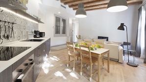 A modern kitchen with a built-in island, wooden dining table, and pendant lighting.
