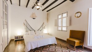 A bedroom with a bed, a chair, a ceiling fan, a window, and a patterned floor. - Charming apartment, first line of the Center Beach, Villajoyosa (Villajoyosa)