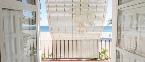 Een balkon met uitzicht op zee, een metalen hekwerk en bloempotten.