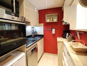 A compact kitchen with a stove, oven, sink, and wooden cabinets.