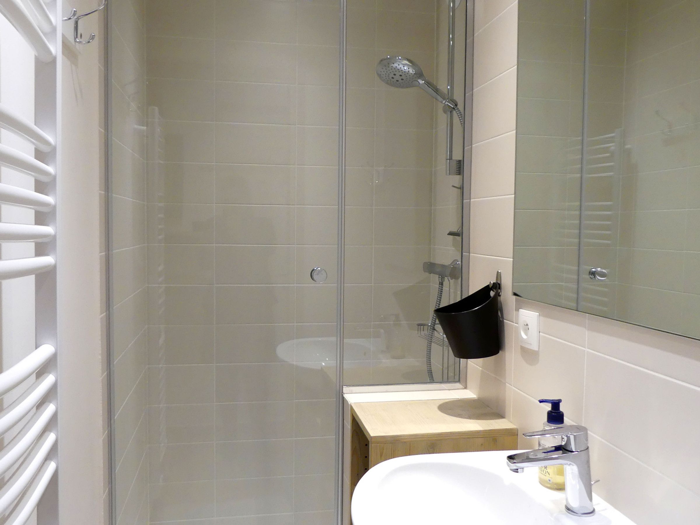 A bathroom with a glass-enclosed shower, a white sink, and a mirror.