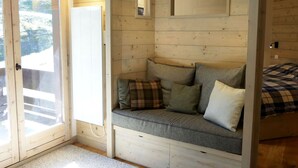 A cozy cabin interior with a built-in bench, a sliding glass door, and a small overhead light fixture. - 3-Room Apartment on the Slopes, Perfect for Families (Méribel)