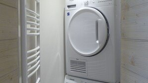 A stacked washer and dryer unit in a laundry room with a white wall and a vented dryer. - 3-Room Apartment on the Slopes, Perfect for Families (Méribel)
