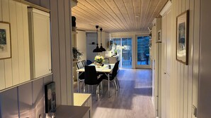 A hallway leading to a dining area with a wooden ceiling, white walls, and a sliding glass door to an outdoor patio. - Beautiful holidayhouse with seaview and wellness area (Broager)