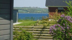 A house with a view of a lake and hills in the background. - Beautiful holidayhouse with seaview and wellness area (Broager)