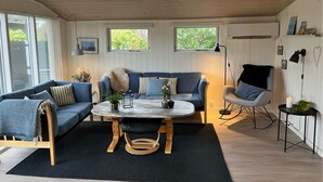 A modern living room with a round coffee table, blue sofas, and a rocking chair. - Beautiful holidayhouse with seaview and wellness area (Broager)