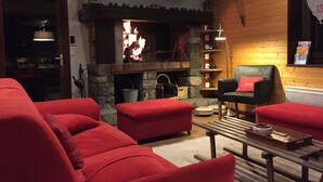 Ein gemütliches Wohnzimmer mit Kamin, roten Sofas und einer Holzwand.