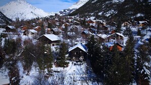 Ein verschneites Bergdorf mit Holzhäusern und einem markanten Hotel im Zentrum.