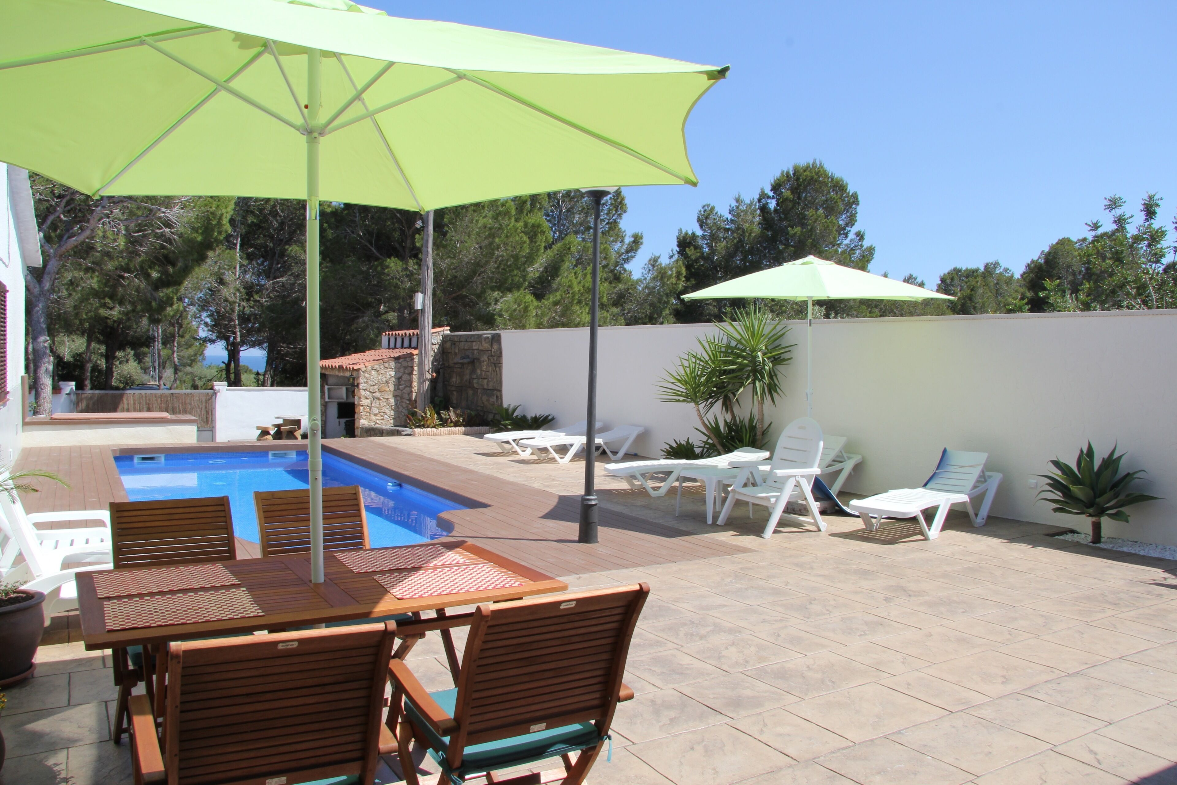 Un patio trasero con piscina, mobiliario de jardín y sombrillas.