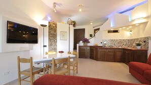 A modern kitchen with a stone backsplash, wooden cabinets, and a built-in TV. - Holiday apartments L'Ea di Lavru 
SEA VIEW 2-rooms apartment-TOP INTERIOR DESIGN (Porto San Paolo)