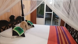 A bed with a striped blanket, a headboard, and two pillows with green and black patterns. - Happy Beach (Unawatuna)