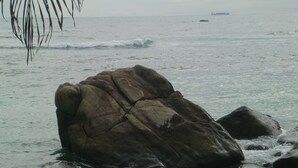 A rocky shoreline with waves crashing against the rocks. - Happy Beach (Unawatuna)