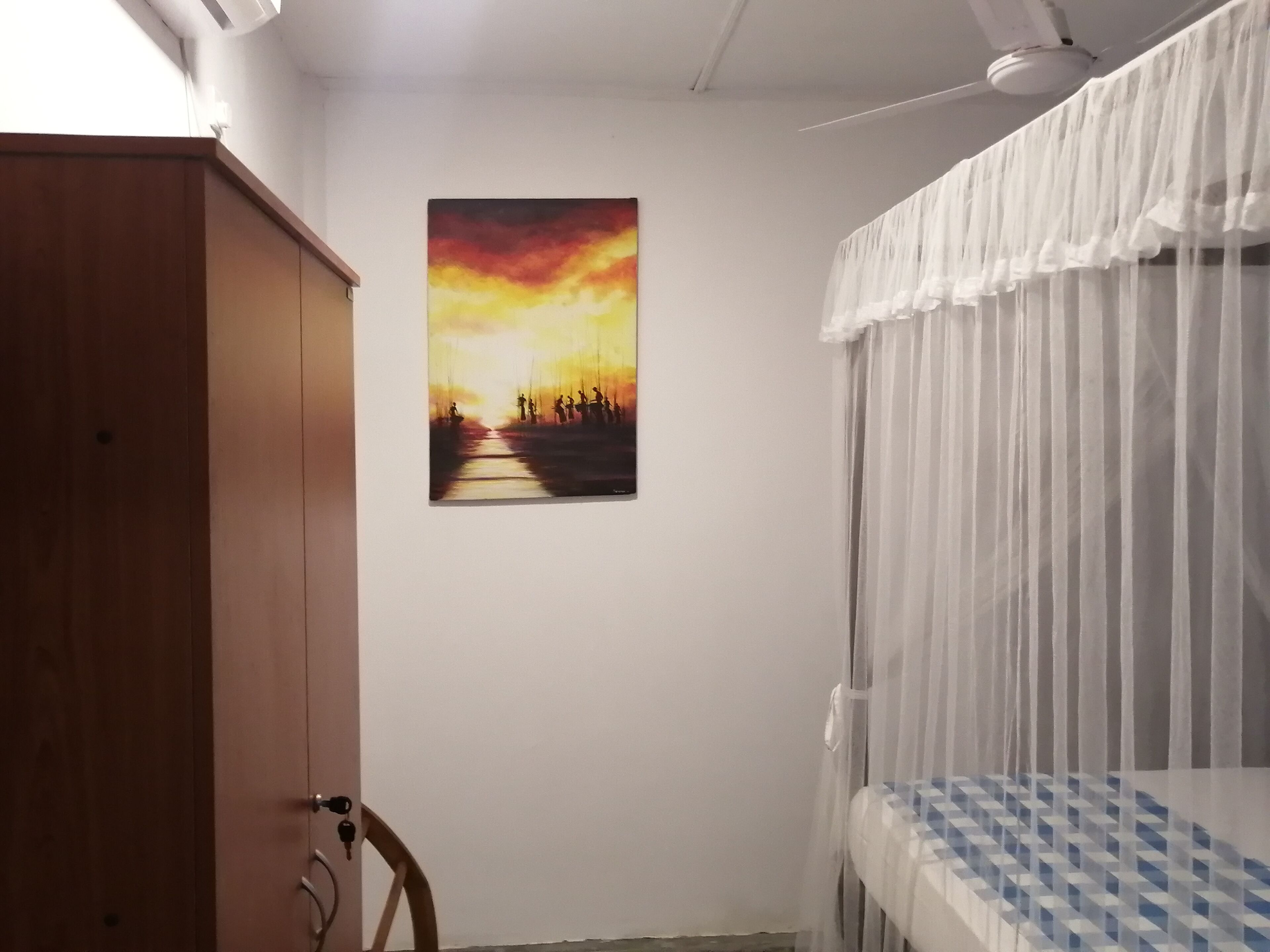 A room with a bed, a wardrobe, and a painting on the wall.