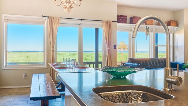 A kitchen with a view of the ocean, a chandelier, and a dining area with a bench.