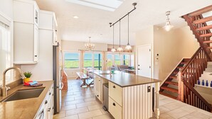 A spacious kitchen with a central island, wooden flooring, and a view to the outdoors.
