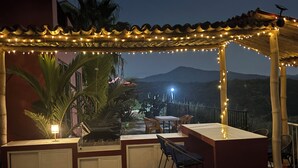 Un patio al aire libre con una zona de bar, asientos y vistas a las montañas.