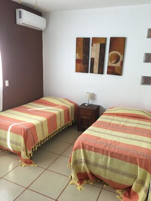 A room with two beds, a nightstand, a lamp, and a wall-mounted air conditioner. - Ocean Front  House, Amazing Views, Infinity Pool, Relaxation (Puerto Angel)