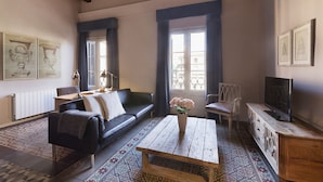 A living room with a sofa, a coffee table, a TV, and a patterned floor.
