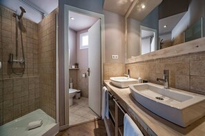 A modern bathroom with a shower, two sinks, and a toilet.