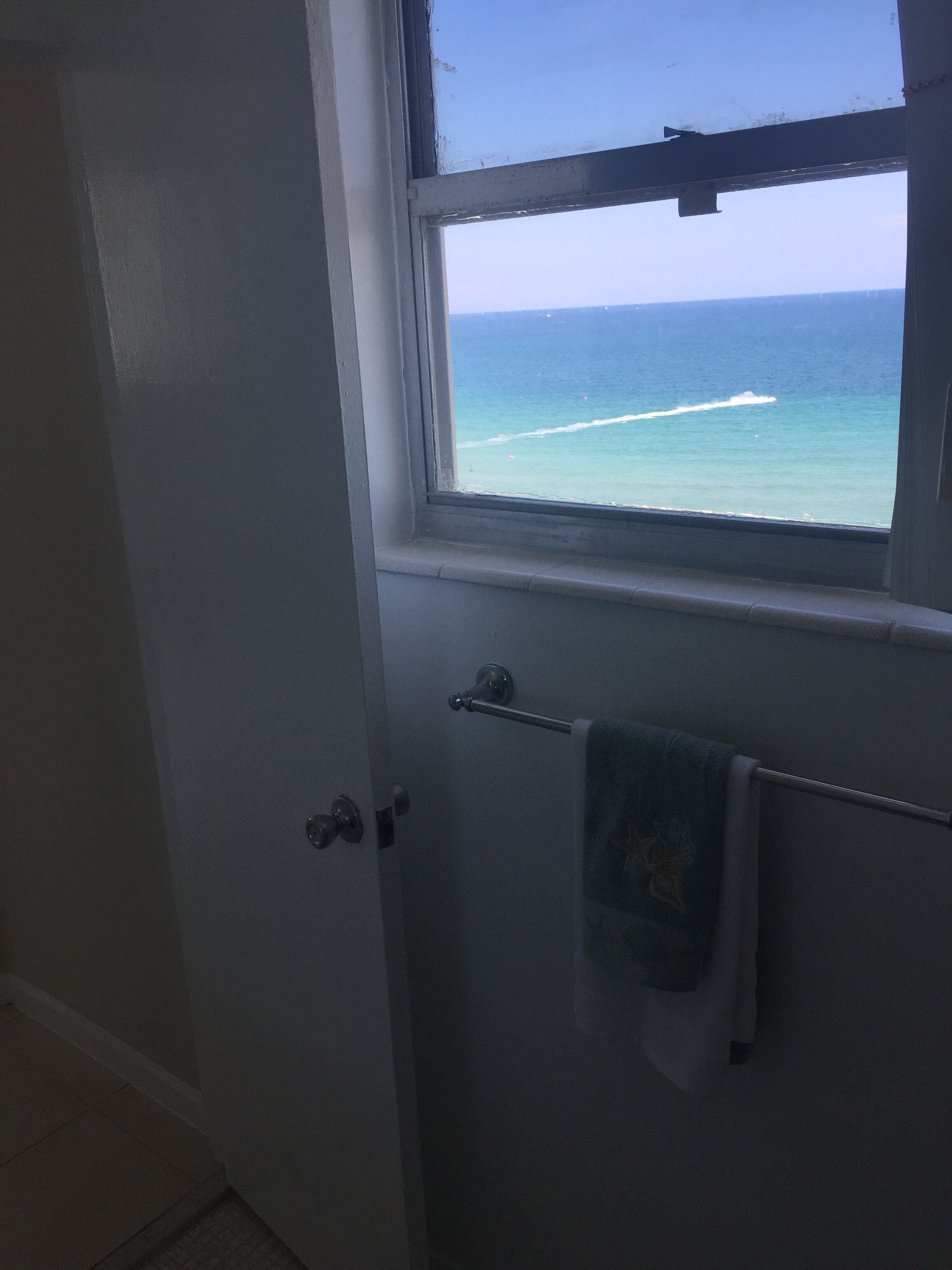 A bathroom with a view of the ocean through a window.