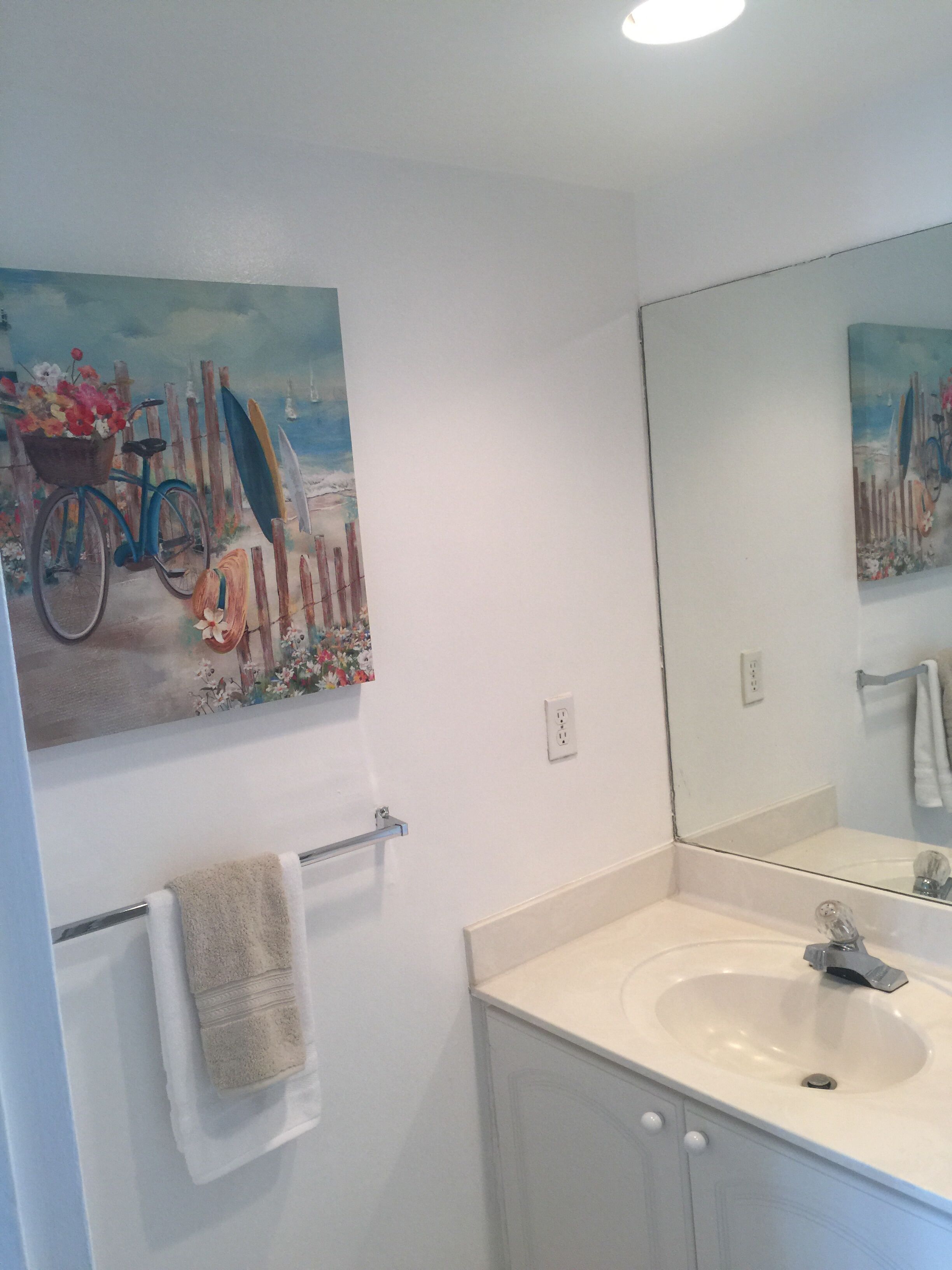 Une salle de bain avec un lavabo blanc, un miroir et un porte-serviettes.