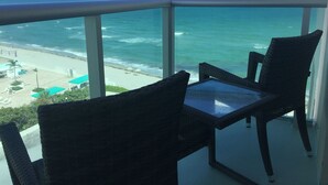 A balcony with wicker chairs and a glass table overlooking a beach and ocean. - RIGHT ON THE BEACH-Direct Oceanview Luxury 2 Bed/2Bath Condo in the Tides Resort (Hollywood)