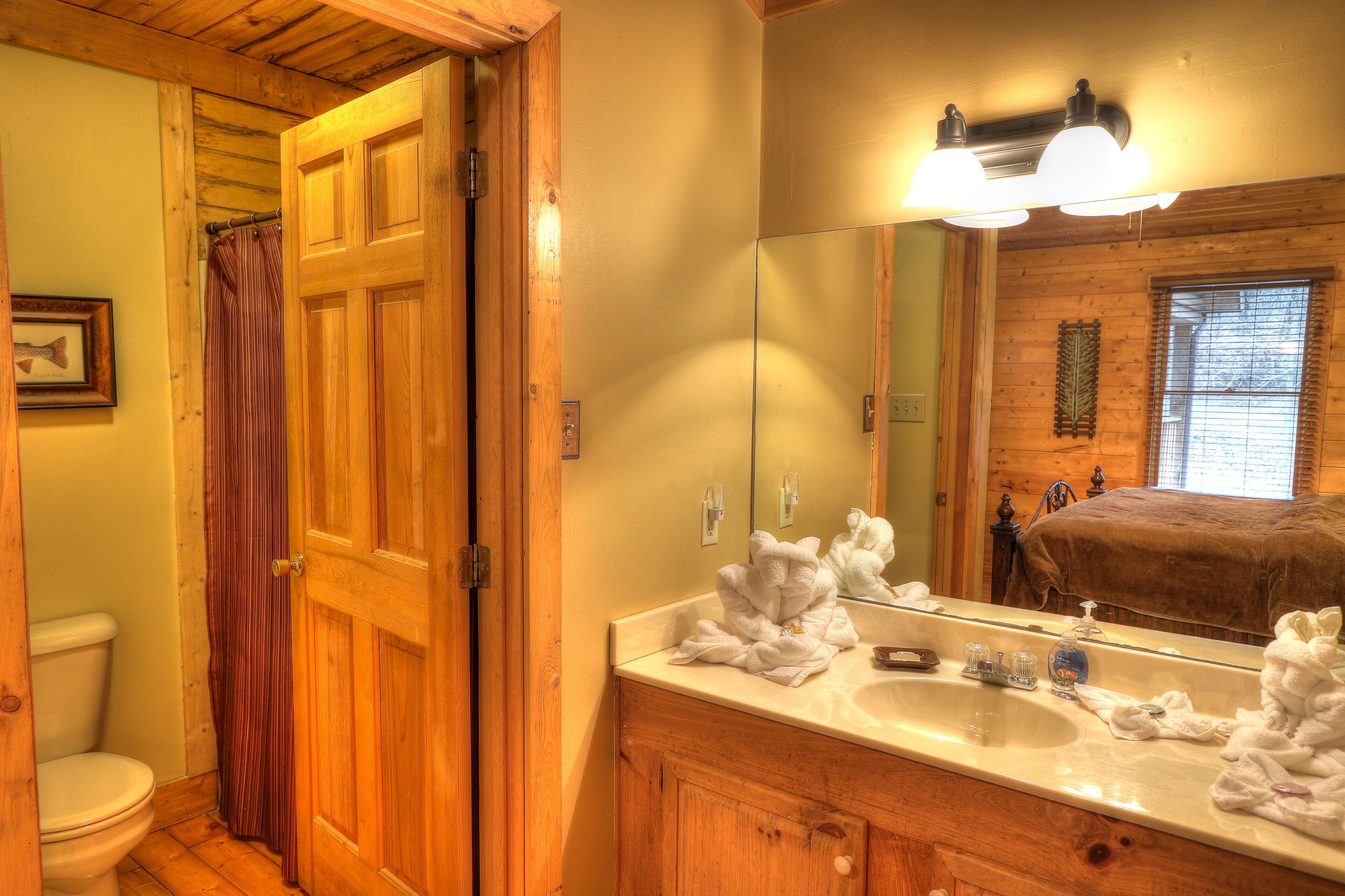 Un baño con puertas de madera, un lavabo, un espejo y una cortina de ducha.