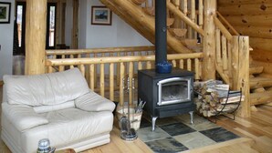 A wooden interior with a staircase, a sofa, a fireplace, and a fan.