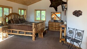 A rustic room with a wooden bed, a desk, and a hanging animal hide.
