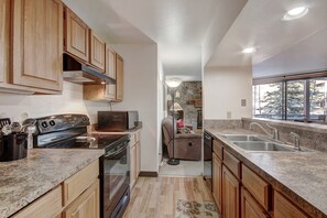 Una cocina con armarios de madera, estufa y pileta.
