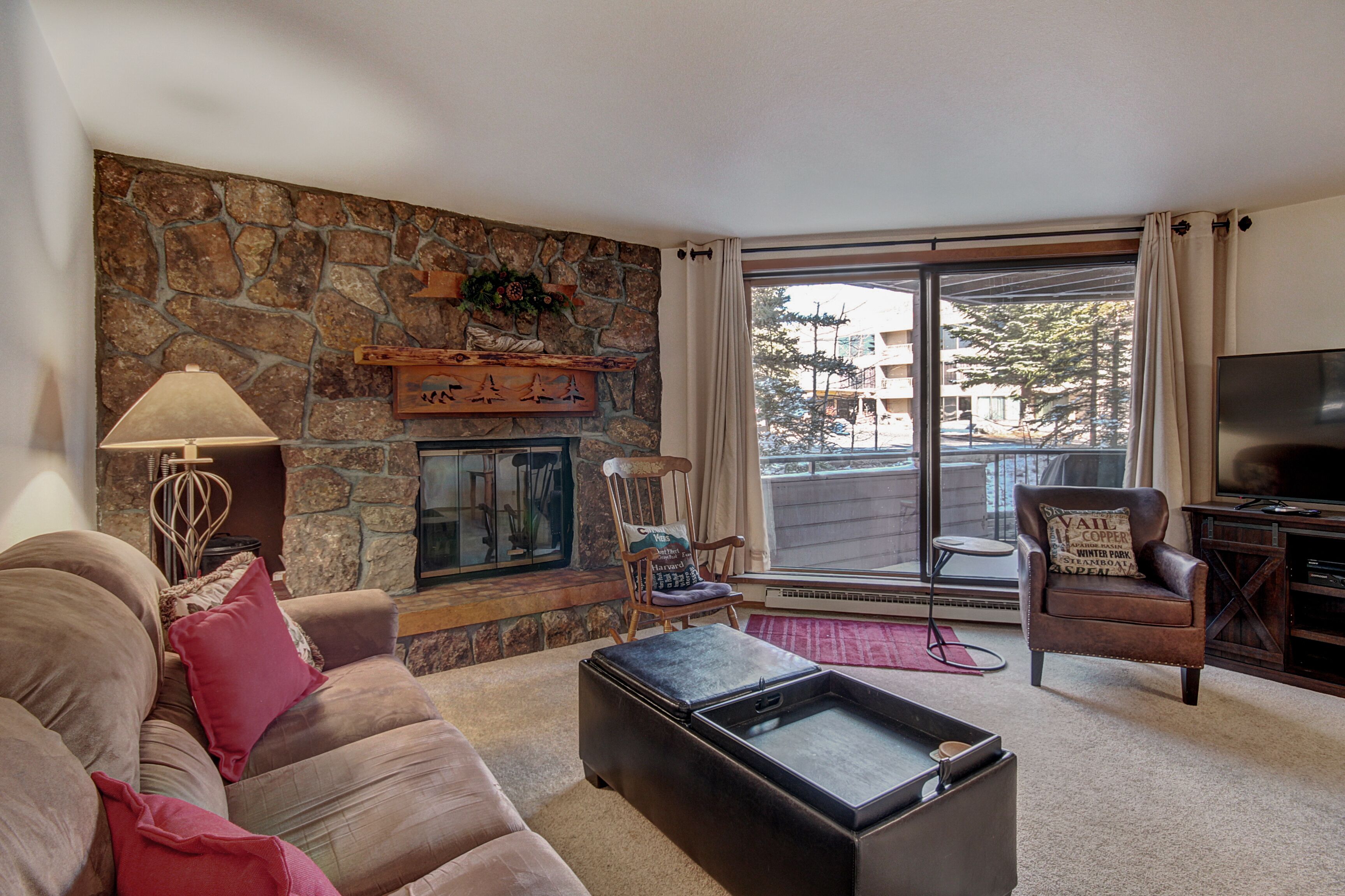 A living room with a stone fireplace, a sofa, a coffee table, and a television.