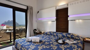 A bedroom with a large bed, a view of the sea, and a balcony with a table and chairs. - Holiday apartments L'Ea di Lavru 
SEA VIEW 3-rooms apartment-TOP INTERIOR DESIGN (Porto San Paolo)