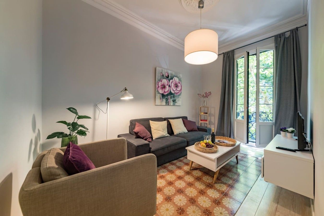 A living room with a sofa, armchair, coffee table, and a painting on the wall.